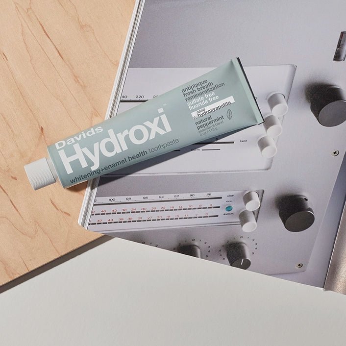 Tube of Davids Hydroxi Peppermint Whitening Toothpaste with Nano Hydroxyapatite on Dieter Rams Book and Wood Background