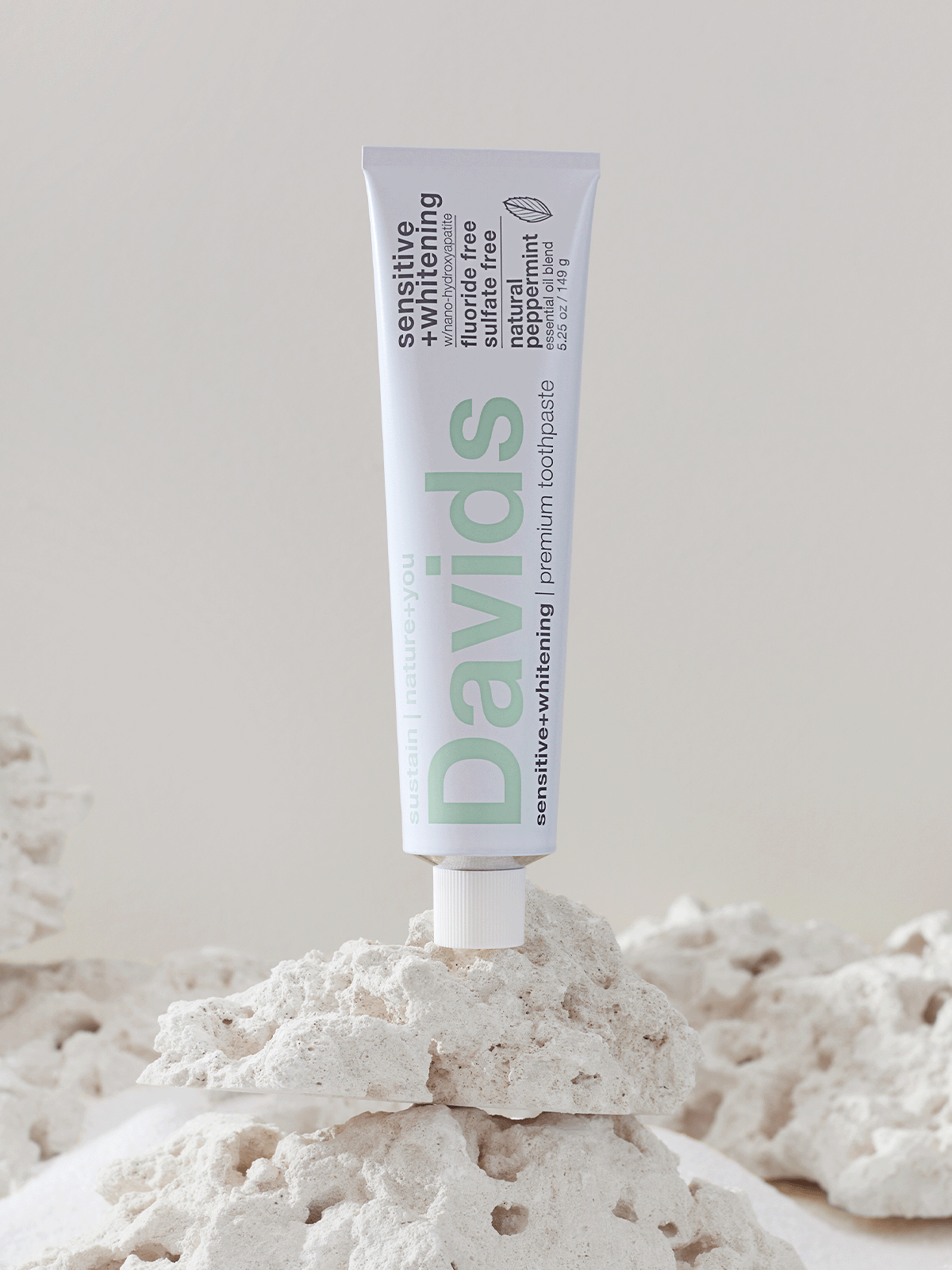 Davids sensitive whitening toothpaste standing upright on a white porous rock