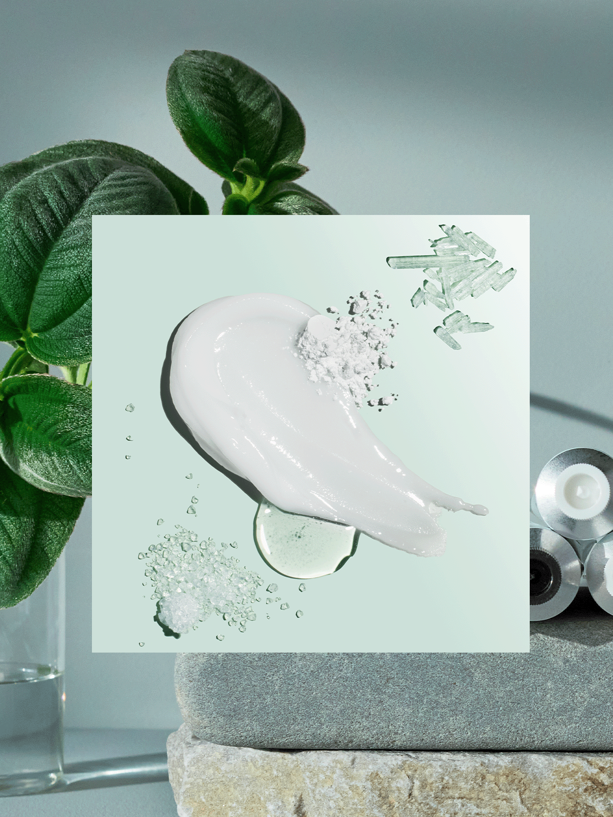 Natural toothpaste ingredients with green leaves and tubes stacked on stones background