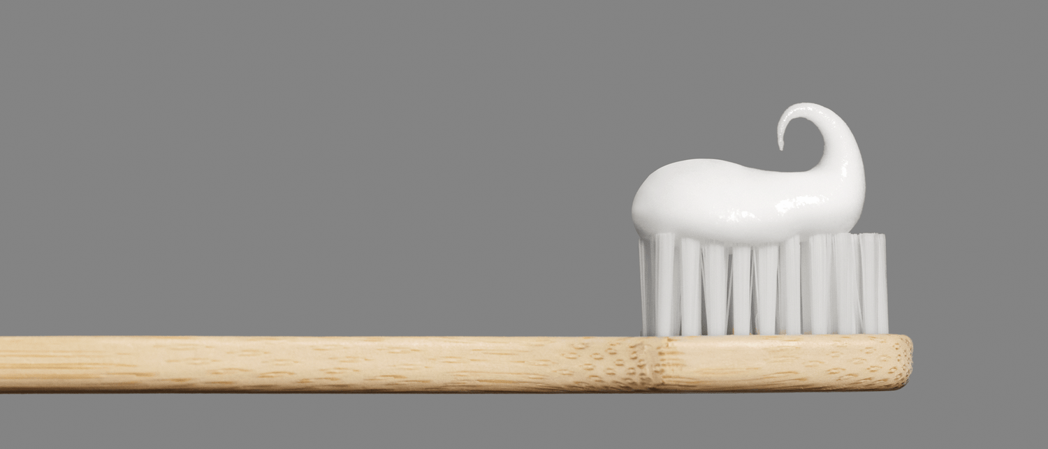 Bamboo toothbrush with white toothpaste on gray background