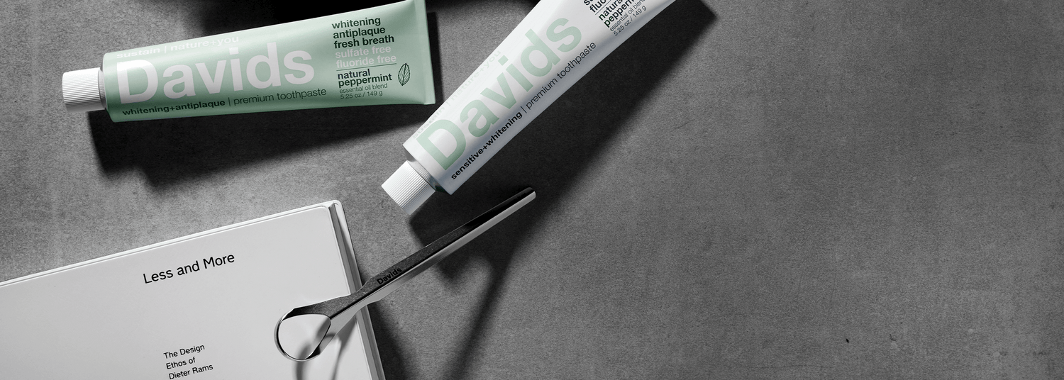 Davids toothpaste, tongue scraper, and book on gray surface