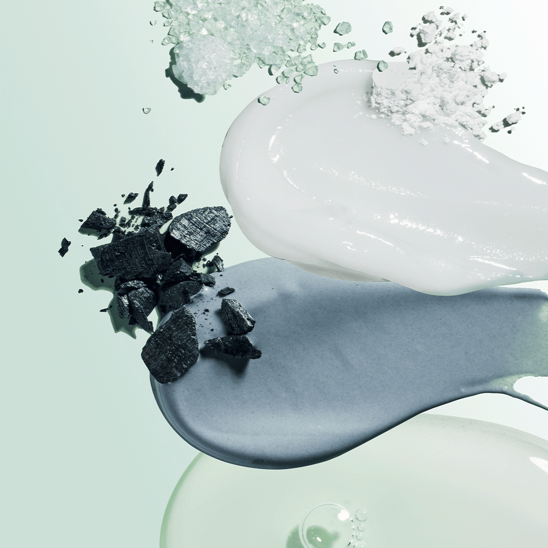 Toothpaste textures with natural ingredients like charcoal, salt, and white clay on a mint background